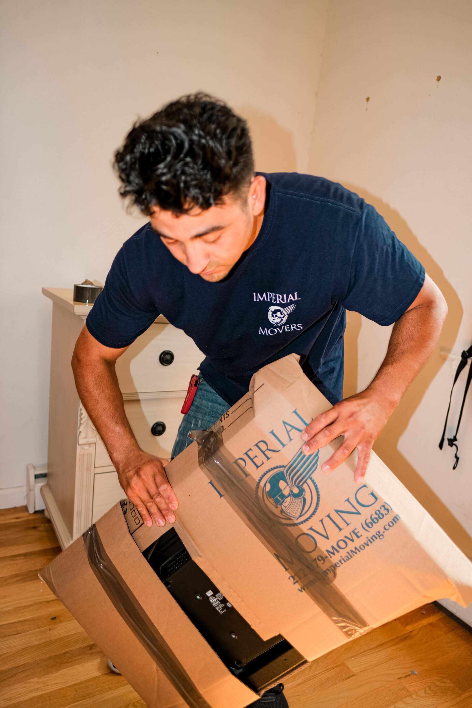 A mover from Imperial Movers packing items in a box